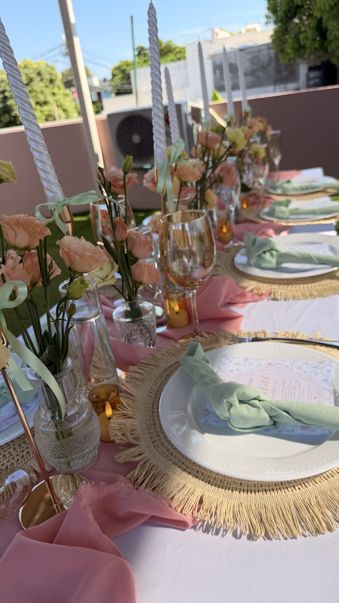 Mesa pastel de evento ETERIA con servilletas suaves, cristalería y decoración floral.